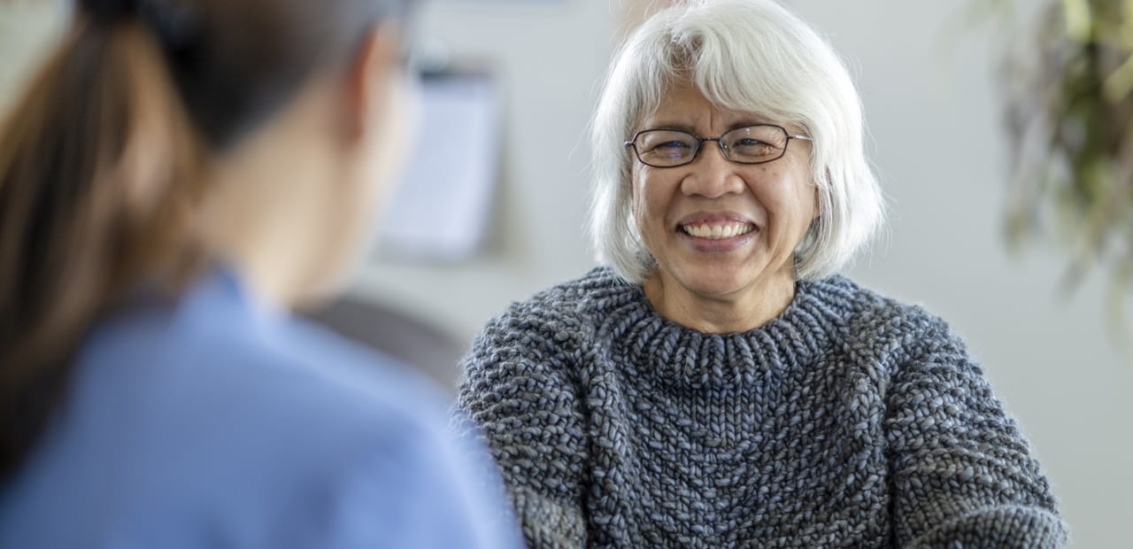 Mature woman smiling at medical professional. 